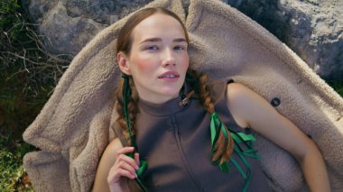 Genç bir kadın, sakin bir şekilde dışarıda uzanıyor. Güzel bir model rahat bir ceketin üzerinde dinleniyor. Sade örgü ören, kameralı model, huzurlu düşüncelere dalmanın keyfini çıkar. Düşünceli gezgin portresi