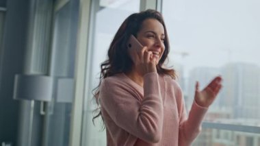 Modern cam dairede hücreden bahseden çekici bir kadın. Gülümseyen kız sabahları dinlenme odasının keyfini çıkarıyor. Kaygısız kadınlar cep telefonlarıyla konuşur. Sakin romantik model akıllı telefon kullan 