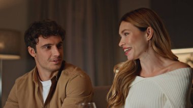 Tatlı ruh eşleri akşam evlerinde şarapla buluşmaktan hoşlanırlar. Mutlu genç çift gülüyor ve romantik bir akşam geçiriyor. Oturma odasında şarap bardakları tutan güzel bir çift.