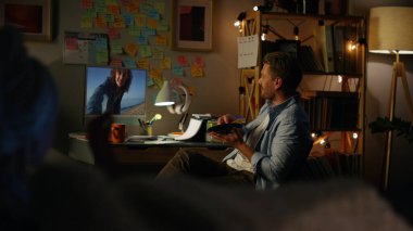 Neşeli bir adamın evdeki arkadaşıyla görüntülü konuşması. Ekranda el sallayan gülümseyen kız tatil haberlerini paylaşıyor. Rahatlamış adam hafta sonu online konferansta konuşuyor. Uzaktan çift sanal buluşmada konuşuyor.