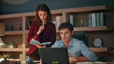 İş stratejisi planlayan ortaklar gece geç saatlerde birlikte çalışıyorlar. Karanlık işyerinde şirket projesini düşünen iki düşünceli çalışan. Ciddi bir adam bilgisayarına bakıyor ve meslektaşıyla tartışıyor..