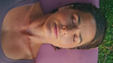 Huzurlu yogi kadın, yeşil çimenlere dikey meditasyon yaparken lastik paspas seriyor. Kapalı gözler sporcu kadın yüzü gün batımında tek başına dinleniyor. Çekici bir bayanın dinlenmesi, nefes egzersizleri yapması. 