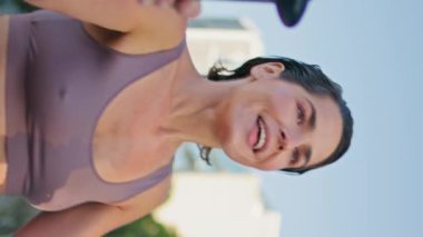 Summer Park 'taki dikey çekimde tatmin olmuş kadın eliptik makine çalışması. Çerçeveden uzaklaşan yorgun sporcu kadın egzersizleri bitiriyor. Gülümseyen kadın açık şehir spor salonunda kilo veriyor.