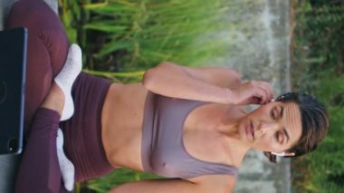 Yoga eğitmeni ders verirken lotus pozu veriyor. Spor kadın kulaklık takıyor, temiz havada tablet bilgisayar izliyor. Sakin, sağlıklı bir bayan sakin yeşil parkta meditasyon yapıyor.