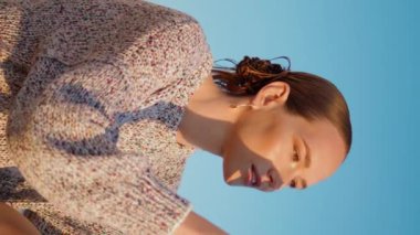 Sahil günbatımında deniz modeli video kaydı dikey olarak. Güzel bir kız göl kenarında akşam güneşinde cep telefonuyla fotoğraf çekiyor. Yaz tatilinde akıllı telefon kullanan kaygısız genç kadın.