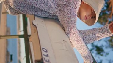 Kadın nehir hafta sonu yalnız başına dikey dinleniyor. Güneş ışığında poz veren güzel kamp kızı akşamları kayığa yaslanıyor. Gündelik tasasız model, yaz tatilinin tadını çıkar. Serene beautiful woman look camera in hat