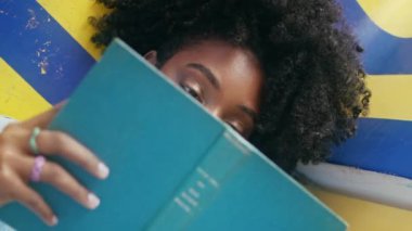 Kitaplı bir öğrenci bankta yatıp üniversite ödevlerini öğreniyor. Modayı takip eden Afro-Amerikalı kız dışarıda dikey odaklı ders kitaplarının arkasına saklanıyor. Kıvırcık kadın modern edebiyatın güneşli günlerinden hoşlanır.