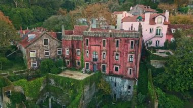 Tarihi konutlar, eski kasaba insansız hava aracı manzarası. Canlı yeşil sarmaşıkla kaplanmış ortaçağ kırmızı tuğlalı evi. Şehir mimarisinde canlı çatılar ve yemyeşil alanlar. Büyüleyici sokaklardaki geleneksel evler