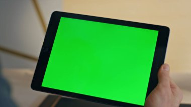 Adamın elleri tablet dokunmatik ekranı araklıyor. Ev işyerinde yakın plan çekimde. İş için elinde yeşil ekran ekran bilgisayarı tutan tanınmamış bir serbest yazar. Modern ofiste kromakey aygıtı kullanan yönetici 