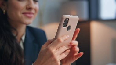 Gülümseyen ofis müdürü akıllı telefon ekranında modern iş yerinde yakın plan oturuyor. Neşeli çekici kadın şirket çalışanı maaş bildirimi alıyor. Güzel genç kız sevinçle mesajlar okuyor. 
