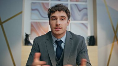 Yaratıcılık ajansında yakın çekim insan kaynakları uzmanı görüntülü görüşme. Pozitif gülümseyen iş adamı kameraya el hareketi yapıyor ve sanal görüntüden zevk alıyor. Neşeli iş adamı Webinar 'ı içeride konuşturuyor.