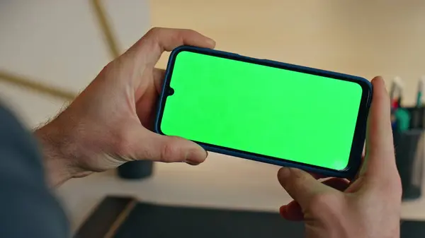 stock image Unknown businessman watching mockup mobile phone sitting at work desk closeup. Man hands holding green screen smartphone in modern office. Manager looking educational online webinar at chromakey cell