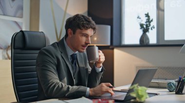 Ofis masasında kahve fincanı yudumlayan birden fazla iş adamı. Dizüstü bilgisayarda çalışan takım elbiseli ciddi bir yönetici. Modern işyerindeki odaklanmış bakışlı patron yazı notlarına bakıyor. İş konsepti