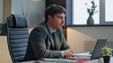 Ajans ofisinde duygusal iş adamı kavgası video görüşmesi. Memnun olmayan patron online dizüstü bilgisayarını şikayet edip masa başı işyerinde kağıtları fırlatıyor. Gergin adam ellerini sallıyor, kızgın hissediyor. 