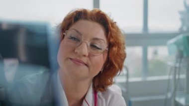 Sağlık hizmetleri kliniğinde teşhis için röntgen analizi yapan bir doktor. Gülümseyen profesyonel radyoloji uzmanı tıbbi incelemeleri inceliyor. Dost canlısı doktor modern poliklinikte teşhisi tartışıyor.