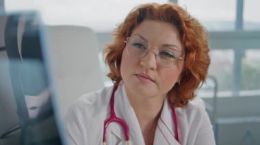 Doktor, sağlık kliniğindeki röntgen görüntülerini inceliyor. Gözlüklü kızıl saçlı profesyonel radyologun portresi tıbbi muayenenin sonucuna bakıyor. Hastalık üzerine düşünen yetenekli bir hekim..