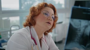 Radyolog klinik muayene odasında röntgen görüntülerine bakıyor. Sağlık hizmetleri atamasında teşhis için tıbbi tetkikleri yapan yetenekli bir doktor. Hasta teşhisini özenli bir doktor açıklıyor.