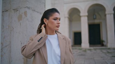 Şehir sokağında beton duvara yaslanan muhteşem bir model. Şehir caddesinde şık bir takım elbiseyle duran güzel bir iş kadını. Şık genç bayan dışarıda buluşmayı bekliyor..