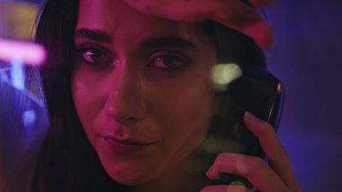 Üzgün bayan neon ışıklı yer portresini arıyor. Depresyondaki üzgün kadın kameraya bakıyor. Canlı renkli kulübelere hiç cevap vermiyor. Aydınlanmış şehirde poz veren melankolik esmer kız.