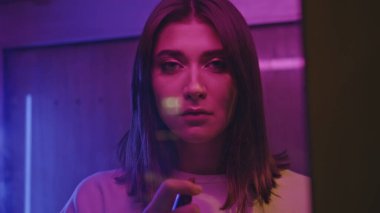 Neon esmer renkli dudaklar çağrı kutusunu kapatıyor. Mutsuz üzgün kadın tek başına canlı ışık portresine bakıyor. Camın arkasında parti yapmaya hazırlanan üzgün model kız. Gece hayatı konsepti