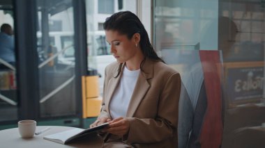 Fotokopi kitabında notlar okuyan güzel bir yazar. Kafe masasında oturuyor. Şehir kafeteryasındaki kahve molasında defterine odaklanmış bir kadın. Kahvehanedeki not defterine harika bir serbest yazar.