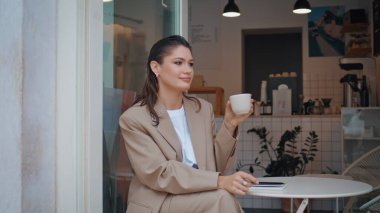 Küçük bir restoranda tek başına espresso içen gülümseyen kadın. Kafeterya masasında oturan muhteşem iş kadını sıcak içeceğin tadını çıkarıyor. Güzel kadın hafta sonu sabah aromatik kahve yudumluyor..