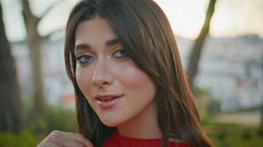 Güzel bir model, kamera görüntüsü, yakın plan. Portre çekici, rahat, yeşil ağaçların altında duran sakin doğa güzelliğinin tadını çıkaran bir kadın. Şık bir genç kız güneşli bir parkta tek başına dinleniyor. 