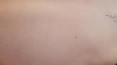 Kumsalda dikey olarak hareket eden esnek kadın vücudu. Arkadan bakıldığında tanınmayan yarı çıplak, dövmeli, doğada yavaşça dans eden bir kız. Meçhul genç bayan narin tenine elleriyle dokunuyor.