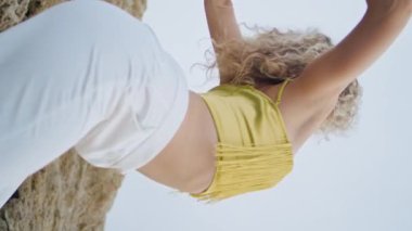 Mavi gökyüzünde dikey olarak hareket eden esnek kız vücudu. İlham verici profesyonel dansçı yaz doğası üzerine çağdaş bir performans sergiliyor. Yetenekli kadın sanatçı dans doğaçlaması yapıyor..