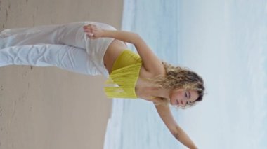 Dans eden güzel bir kadın kumsalda sakin bir yaz akşamı dikey meleğinin tadını çıkarıyor. Modern sanatçı, sadece ıslak deniz kıyısına şehvetle ayak basıyor. Çağdaş stilde çalışan kadın koreograf.