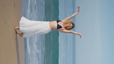 Romantik kız kumsalda dans ediyor yaz akşamı dikey meleğinde. Profesyonel kıvırcık koreograf deniz kıyısında zarif hareketler yapıyor. Okyanusta dans eden şehvetli dansçı.