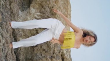 Modern stil dansçı taş üzerinde vücudu dikey olarak hareket ettiriyor. Güzel esnek kadın yaz doğasında modern dans gösterisi yapıyor. Kıvırcık kız dansçı olağanüstü koreografi çalışması yapıyor.