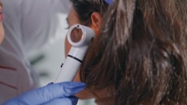 Klinikteki kulak muayenesinde otoskop kullanan profesyonel bir doktor. Sağlık uzmanı kadın hasta sağlığını sağlık muayenesinde kontrol ediyor. Doktor ziyaretçiyi özel ekipmanlarla muayene ediyor..