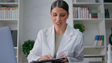 Hastane ofisindeki görüntülü konuşma sırasında sağlık uzmanı konuşuyor. Bilgisayardan arayan kadın doktor tedavi analizine odaklanmış. Modern klinikte tıbbi tavsiyeler veren bir doktor..