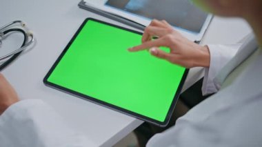 Sıhhiyeci, poliklinikte krom anahtar tableti gösteriyor. Kimliği belirsiz kadın doktor, sağlık hizmetlerinde yeşil ekran cihazına dokunuyor. Hekim, sağlık hizmetleri tıbbi danışmanlığında model bilgisayar kullanıyor..