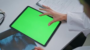 Klinikteki sağlık danışmanlığında yeşil ekran tableti kullanan bir doktor. Bilinmeyen kadın doktor krom anahtar cihazının tıbbi verilerini inceliyor. Modelleme aygıtında tıbbi hasta bilgileri aranıyor.