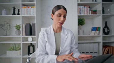 Klinikteki webcam tarafından yakın planda sağlıkçı danışmanlığı. Tablet ekranında tıbbi verileri inceleyen bir kadın doktor konuşuyor. Ciddi bir doktor çevrimiçi toplantı yaparak testleri açıklıyor..