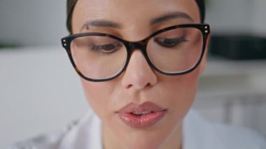 Klinikteki doktor muayenehanesinde portre doktoru konuşuyor. Gözlüklü deneyimli kadın hekim hastanede bilinmeyen bir hastaya danışıyor. Sağlık hizmetleri danışmanlığı yakın çekim.