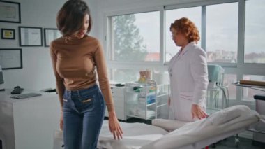 Klinik muayene odasında profesyonel sağlık hizmeti veren bir hasta var. Poliklinikte sağlık danışmanlığı için hazırlanan işçi kıyafetli doktor. Genç bayan tıbbi kanepede oturup sağlık kontrolü bekliyor..