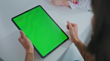 Kadın klinikte zum yapan yeşil ekran tableti uzatıyor. Tanımlanamayan hasta dijital cihazdaki tıbbi verileri tarıyor. Çoklu klinik ziyaretçisi masadaki krom anahtar bilgisayarını tutuyor.
