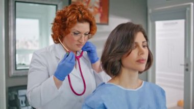 Doktor, modern klinikte steteskopla nefes kontrolü yapıyor. Beyaz cüppeli sağlık görevlisi hasta sağlık kontrolü yapıyor. Profesyonel muayene yapan ciddi bir doktor..