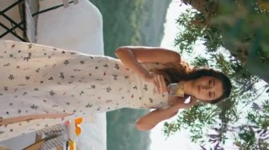 Siesta 'lı kadın terasta dikey su içiyor. Gevşemiş narin kız, ağacın altında limonata yudumluyor ve balkonda tek başına yürüyor. Romantik model panoramik mekanda soğuk sıvı içecekten keyif alıyor..