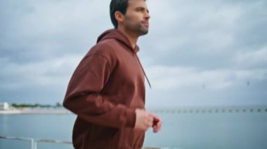 Liman kapanışında bulutlu bir günde koşan sporcu. Sağlıklı bir adam kasaba körfezinde sprint antrenmanında eğleniyor. Tıraşsız esmer kadın sabahları kardiyo yapıyor. Maratondan önce enerjik adam egzersizi 