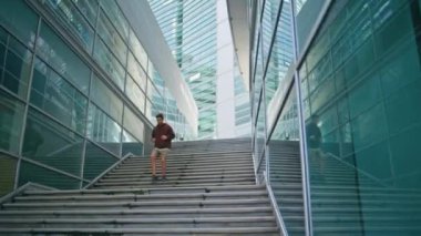 Koşucu sabahları modern mimari eğitimi alıyor. Merdivenlerde koşan şehirli fitness adamı. Uzun cam binalar arasında koşuşturan dinamik bir atlet. Kararlı sporcu enerjiyle koşuyor. Etkin yaşam biçimi.