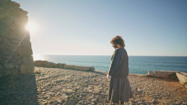 Yalnız kız akşamları Marine Hill 'de yürüyor. Huzurlu kadın gün batımında dağ manzarasında duran kayalara bakıyor. Gezgin rahatlatıcı okyanus manzarası