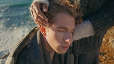 Kıvırcık adam, güneş ışığı okyanus kıyısında birbirine bağlanmış bir kız arkadaşla karşı karşıya. Kimliği belirsiz, erkek arkadaşının kafasını okşayan romantik deniz buluşmasında hassas bir anın tadını çıkaran bir kadın. Şehvetli aşıklar akşam deniz kıyısında sarılıyorlar.