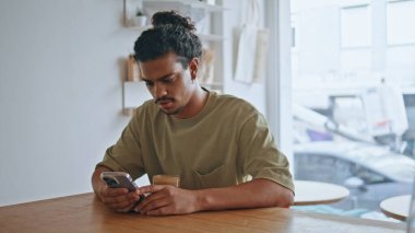 Kafe masasında oturan Latin bir adam akıllı telefon ekranını tek başına kapatıyor. Kıvırcık Brezilyalı hippi cep telefonuyla sosyal medyada geziniyor. Sıcak kahve dükkanında erkek serbest mesajlaşması.. 