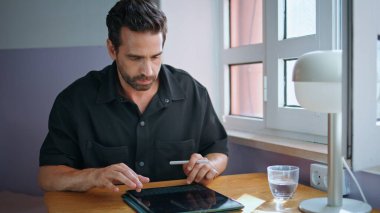 Tablet yazan yakışıklı serbest yazar tek başına oturma masasını kapatır. Bilgisayarla internet bilgilerini arayan odaklanmış sakallı iş adamı. Modayı takip eden akıllı adam gün ışığında internette sohbet ediyor..
