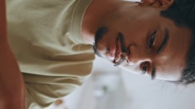 Curly Freelancer, kafeteryadaki internet iletişimi için cep telefonu kullanıyor. Akıllı telefon dikey görüntüsünde gülümseyen Latin adam. Bıyıklı adam kahve dükkanında sosyal ağlarla konuşuyor.