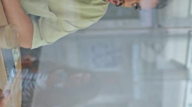 İki dost canlısı adam kafeterya masasında oturarak konuşuyor. Pencereden, gülümseyen erkek çiftin kafede buluşmalarından zevk aldıklarını izleyin. Neşeli, çok ırklı adamlar birlikte vakit geçiriyorlar..